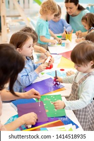 Development Learning Children In Preschool. Children's Project In Kindergarten. Group Of Kids And Teacher Cutting Paper And Gluing With Glue Stick On Art Class In Kindergarten Or Daycare