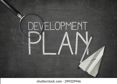 Development Plan Concept On Black Blackboard With Empty Paper Sheet And Coffee Cup