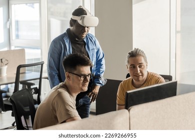 IT Development Team Working on VR Project. Black man wearing VR headset. Virtual world. Diverse men programmers using VR technologies and computer to create video game