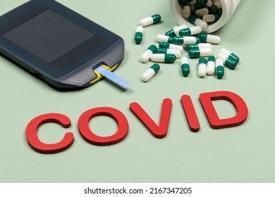 Device To Measure Blood Glucose, Vitamin D Box And The Word Covid Written In Green Background