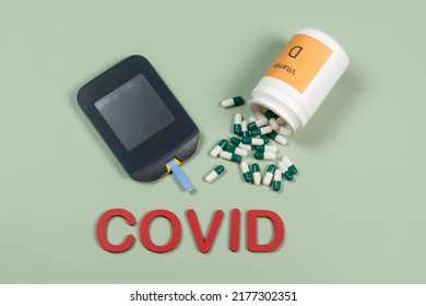 Device To Measure Blood Glucose, Vitamin D Box And The Word Covid Written In Green Background