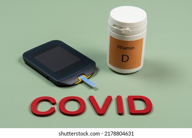 Device To Measure Blood Glucose, Vitamin D Box And The Word Covid Written In Green Background