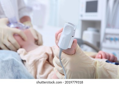 A Device For Measuring The Concentration Of Oxygen In The Blood On A Child's Finger. Preparing For Surgery. The Child Is Under Anesthesia. Oxygen Face Mask. Life Saving. The Child Is Out Of Focus.