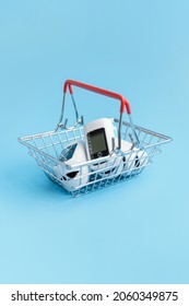 The Device Is A Pulse Oximeter In A Miniature Supermarket Cart On A Blue Background. Vertical Foto