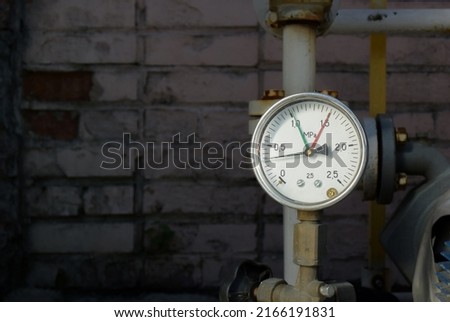 A device that measures pressure against a brick wall. Round barometer built into the tube. Measuring round scale with arrows.