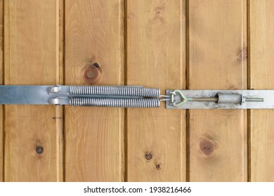 A Device For Tightening Wood Boards When Drying Out. Metal Springs, Adjustment Nut With Hinge. Wall Of Vertical Planks. Concept Of Eliminating Gaps In The Wood With A Clamp.