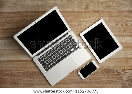 Devices with blank screens on wooden background, top view. Mock up for design