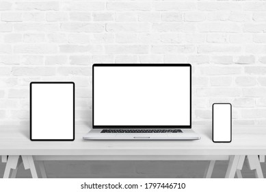 Devices with isolated screens for responsive web design promotion. Web design studio concept on white wooden desk and brick wall in background