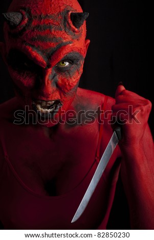 Devil attacking with a knife, black background.