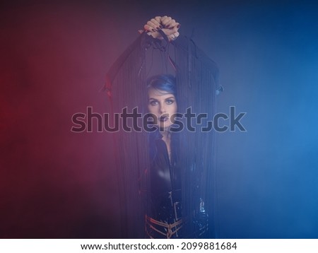 Devil. Funny imp with black horns and latex suit with shibari at Halloween party. The devil costume. smoke in red and blue, atmosphere of underworld.