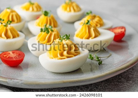 Deviled eggs with cheese, mustard and microgreens on top on a plate for Easter