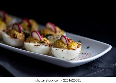 Deviled eggs garnished with smoked paprika , sliced radish , and chopped basil. - Powered by Shutterstock