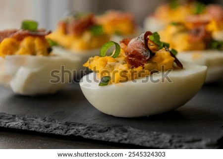  deviled eggs topped with crispy bacon and green onion, creating a savory and colorful appetizer. Perfect for party starters, gatherings, or holiday platters