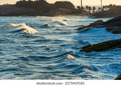 Devil's Beach in Ipanema with its waves and hidden between the rocks during the sunset of the city of Rio de Janeiro in summer
