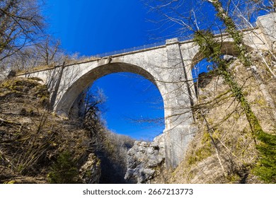 Devil's Bridge spanning the Loue River gorge in Crouzet Migette, showcasing its architectural marvel against a clear blue sky