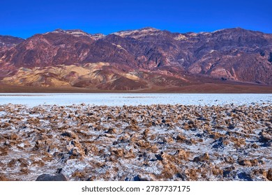 Devil's Golf Course Salt Formations and Colorful Desert Mountains Under Blue Sky