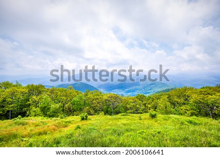 Devil's Knob Overlook green grass field meadow at Wintergreen resort town village in Blue Ridge mountains in summer clouds mist fog