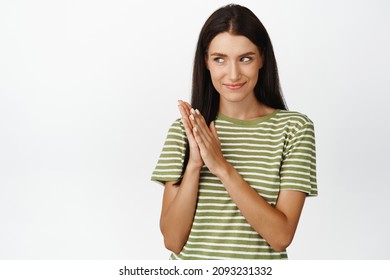 Devious woman rubbing her hands, scheming something with coy face expression, standing over white background
