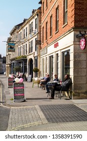 Devizes, Wiltshire, England, UK. March 2019.  Customers Seated Outside A Pub And Coffee Shop On The Main Street.