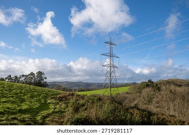 Devonshire countryside with rolling green fields and blue skies. Electricity pylons cross the landscape. Hiking and country walks. English rural landscape.