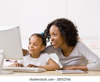 Devoted Mother Helping Girl Do Homework On Computer