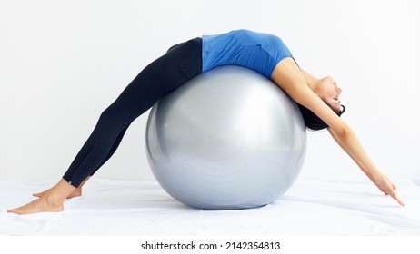 Devoted To Total Wellbeing. Young Woman Stretched Over A Swiss Ball While Isolated On White.