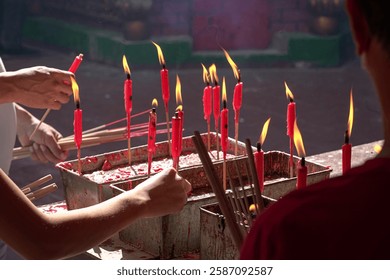 Devotee lighting candle inside a chinese taoist temple. Religion or chinese holiday concept.