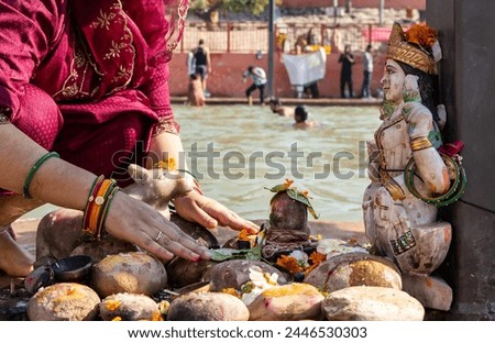 devotee praying for holy god shivalinga with flowers at river shore at morning