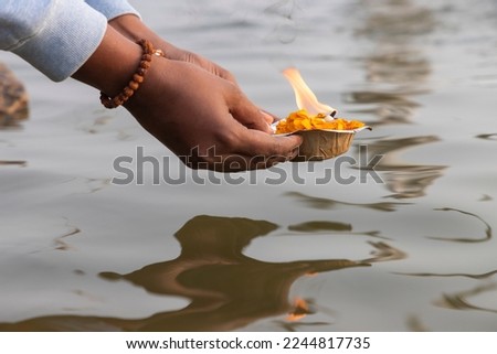 A devotee releasing the worship lamp diya as a ritual in the river Ganga at Varanasi, Uttar Pradesh