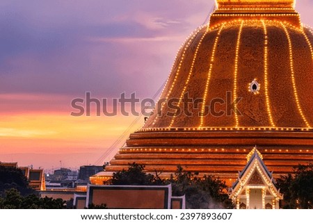 Devout buddhists people climb up to light decoration the grand golden pagoda Phra Pathom Chedi on colorful sunset sky in annual festive at Nakhon Pathom, Thailand
