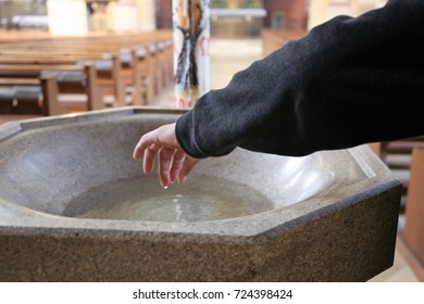 Devout Christian dipping his fingers in holy water