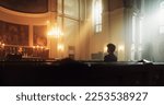 A Devout Christian Sits Piously In A Grand Church, Folding Hands for Praying, Contemplating Their Earthly Life. Parisher Seeks Moral Guidance From the Faith. Religious Atmosphere Of The Sacred Space