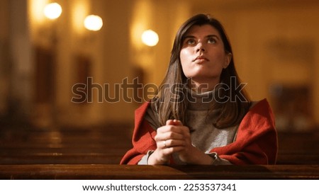 A Devout Christian Woman Sits Piously In a Church, Folding Hands For Praying, Seeks Guidance From Her Religious Faith and Spirituality. Spirit of Christianity and Belief in the Goodness of God