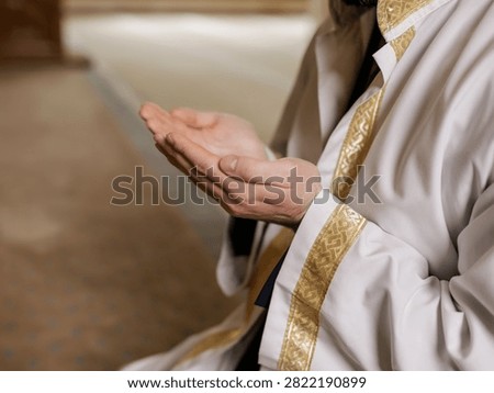 Devout religious man wearing traditional white robes holds his open hands up during daily sincere prayer