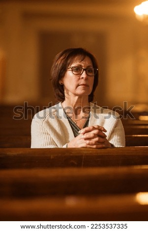 A Devout Senior Christian Woman Sits Piously In a Church, Seeks Guidance From Her Religious Faith and Spirituality. Spirit of Christianity and Belief in the Goodness of God, Folding Hands For Praying,