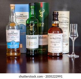 Brasília, Df, Brazil, September 2, 2021. Scotch whiskey single malt Glenfiddich 12 years old, The Balvenie and The Glenlivet, in selective focus on a rustic wooden table.