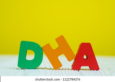 DHA text alphabet on white wooden table. yellow wall background with copy space for add text.