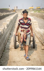 DHAKA, BANGLADESH - DECEMBER 27, 2021: A Young Underaged Kid Is Doing Child Labour At The Brick Kilns, The Stone And Brick Factory 