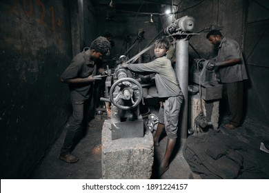 DHAKA, BANGLADESH - JANUARY 10, 2021: A local dark factory or sweatshop in Bangladesh where underaged young kids are doing child labour under dangerous and risky circumstances without compliance
