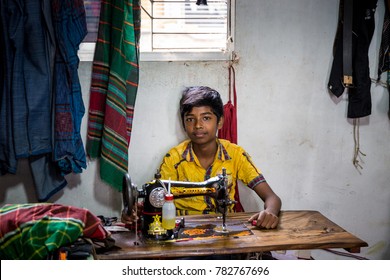 DHAKA, BANGLADESH - JANUARY 6, 2017: Young Boy Wearing A Yellow Shirt Behind A Sewing Machine Doing Child Labour