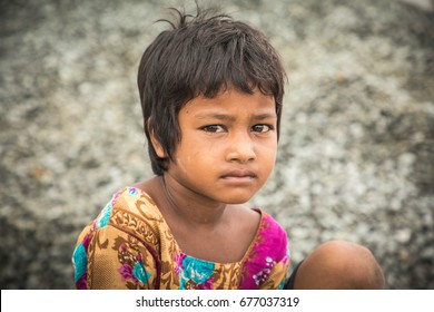 DHAKA, BANGLADESH - JULY 10, 2017: A young homeless girl is sitting at a bridge in dirty clothes and begging