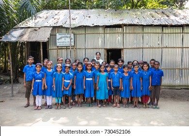 DHAKA, BANGLADESH - NOVEMBER 6, 2017: A slum school in the village of Bangladesh with the total class in bright blue school uniforms is standing in front of their make shift classroom