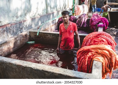 DHAKA, BANGLADESH - OCTOBER 03, 2021: Underaged Workers Or Child Labour In The Textile Industry Where They Are Dying The Garments And Textiles By Hand In A Bath Full Of Dying Chemicals 