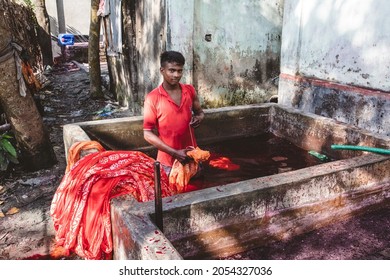 DHAKA, BANGLADESH - OCTOBER 03, 2021: Underaged Workers Or Child Labour In The Textile Industry Where They Are Dying The Garments And Textiles By Hand In A Bath Full Of Dying Chemicals 