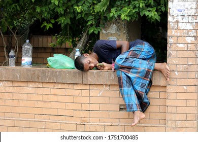 Dhaka, Bangladesh-June 07, 2020: People, who went to Mugda Hospital for COVID-19 tests, doze off on walls of a front-yard garden of hospital in afternoon hours after waiting for his turns to be tested