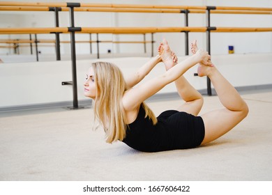 Dhanurasana Yoga Pose (Bow Pose). Yoga Poses To Burn Belly Fat. Abdominal Stretching. Young Attractive Blond Girl In Black Shorts In A Dance Class.