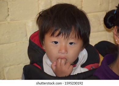 Dharamshala, India 2019 : Cute Fair Complexion Chinese Baby Girl Putting Her Finger Inside Her Mouth. Her Nose Is Running And She Is Looking At The Camera