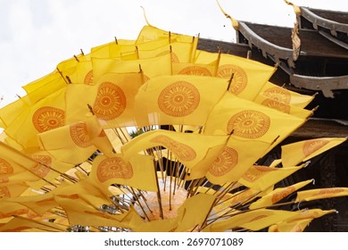 Dharmacakra yellow flags representing the wheel of Dhamma buddha on a buddhist temple in Chiang Rai, Thailand