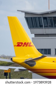 DHL aircraft cargo distribution centre at East Midlands Airport, Leicestershire 12.5.2021 Yellow Boeing 767 Aeroplane jumbo jet being loaded with packages. Warehouse control tower behind company logo
