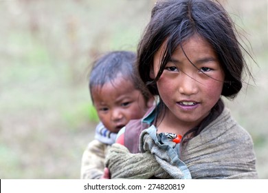 DHO TARAP, NEPAL - SEPTEMBER 10: Nepalese girl with her baby brother walkig on the road on September 10, 2011 in Dho Tarap village, Upper Dolpo, Nepal